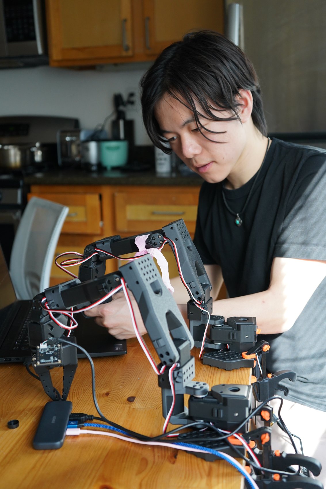 A member assembling the robot arm at a kitchen table